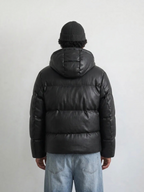 BROCK men's black hooded puffer jacket in a leather-look finish, worn by a man in a beanie, back view.