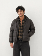 BROCK men's dark brown faux leather puffer jacket with a high collar, worn over a plaid shirt and black jeans.