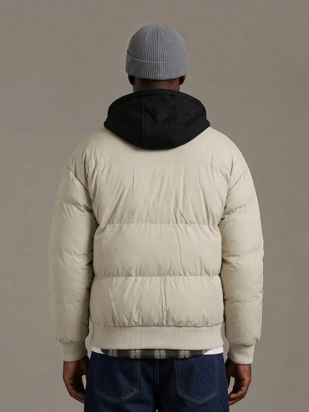 Back view of a man wearing a beige BROCK KZ DIFFUSION puffer jacket with a contrasting black detachable hood.