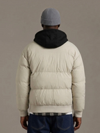 Back view of a man wearing a beige BROCK KZ DIFFUSION puffer jacket with a contrasting black detachable hood.