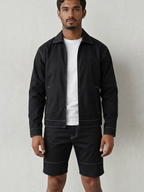 BROCK men's black two-piece jacket and trousers set with white contrast stitching worn over a white t-shirt