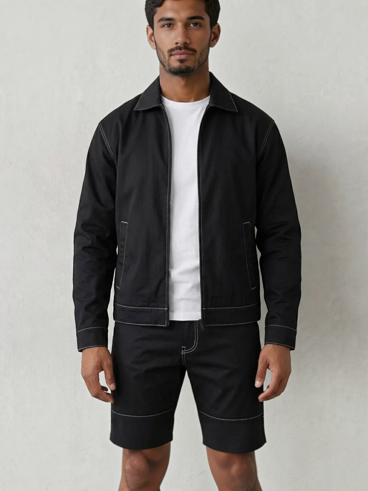 BROCK men's black two-piece jacket and trousers set with white contrast stitching worn over a white t-shirt