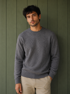 Man wearing a grey KZ DIFFUSION wool blend sweater with a crew neck against a green wooden wall, BROCK style.