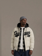 BROCK beige puffer jacket with black Chicago lettering and removable hood worn by a man in a grey beanie