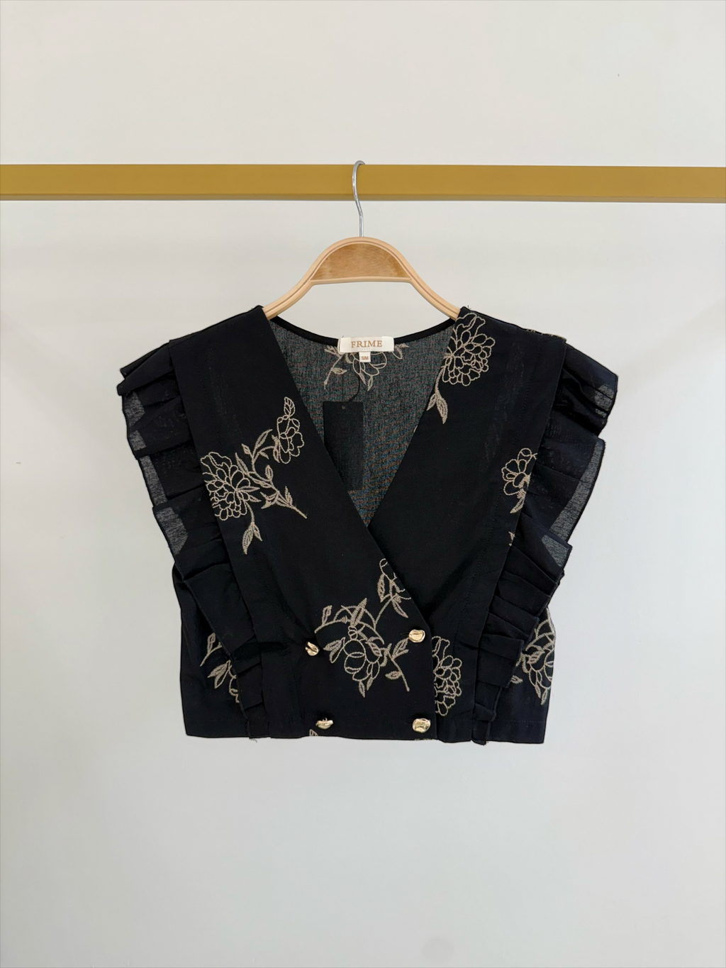 Top court noir BROCK FRIME en coton avec imprimé floral, col en V, boutons dorés et détails à volants sur les épaules