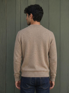 BROCK KZ DIFFUSION beige wool blend sweater worn by a man, back view against a green wooden wall.