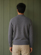 Back view of a man wearing a grey KZ DIFFUSION wool blend sweater with a ribbed collar and cuffs against a green wall