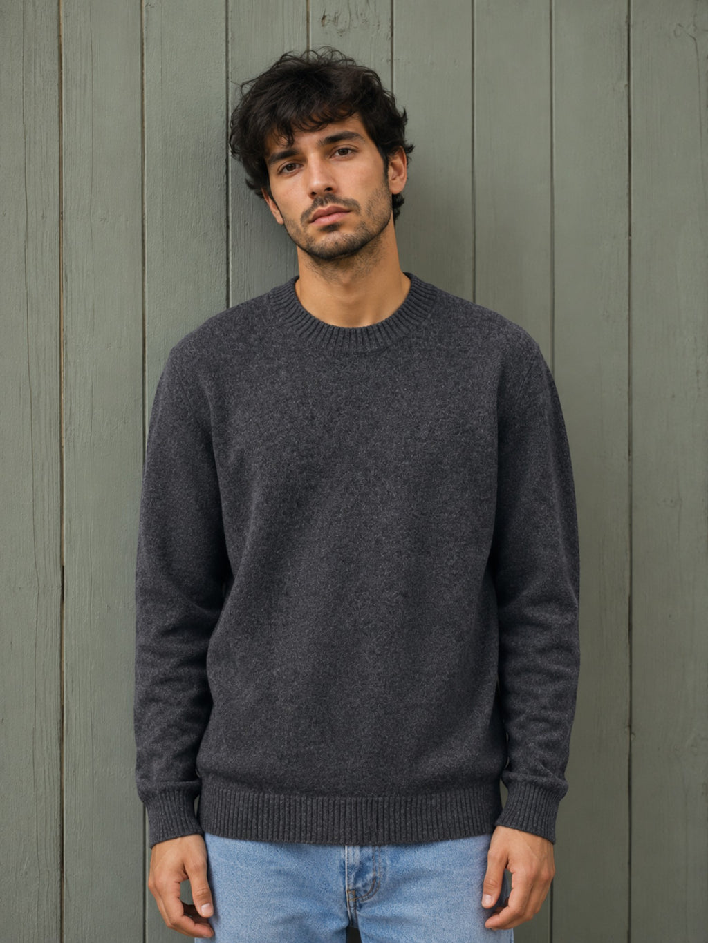 BROCK KZ DIFFUSION grey wool blend crew neck sweater worn by a man against a rustic wooden wall