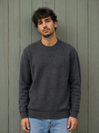 BROCK KZ DIFFUSION grey wool blend crew neck sweater worn by a man against a rustic wooden wall