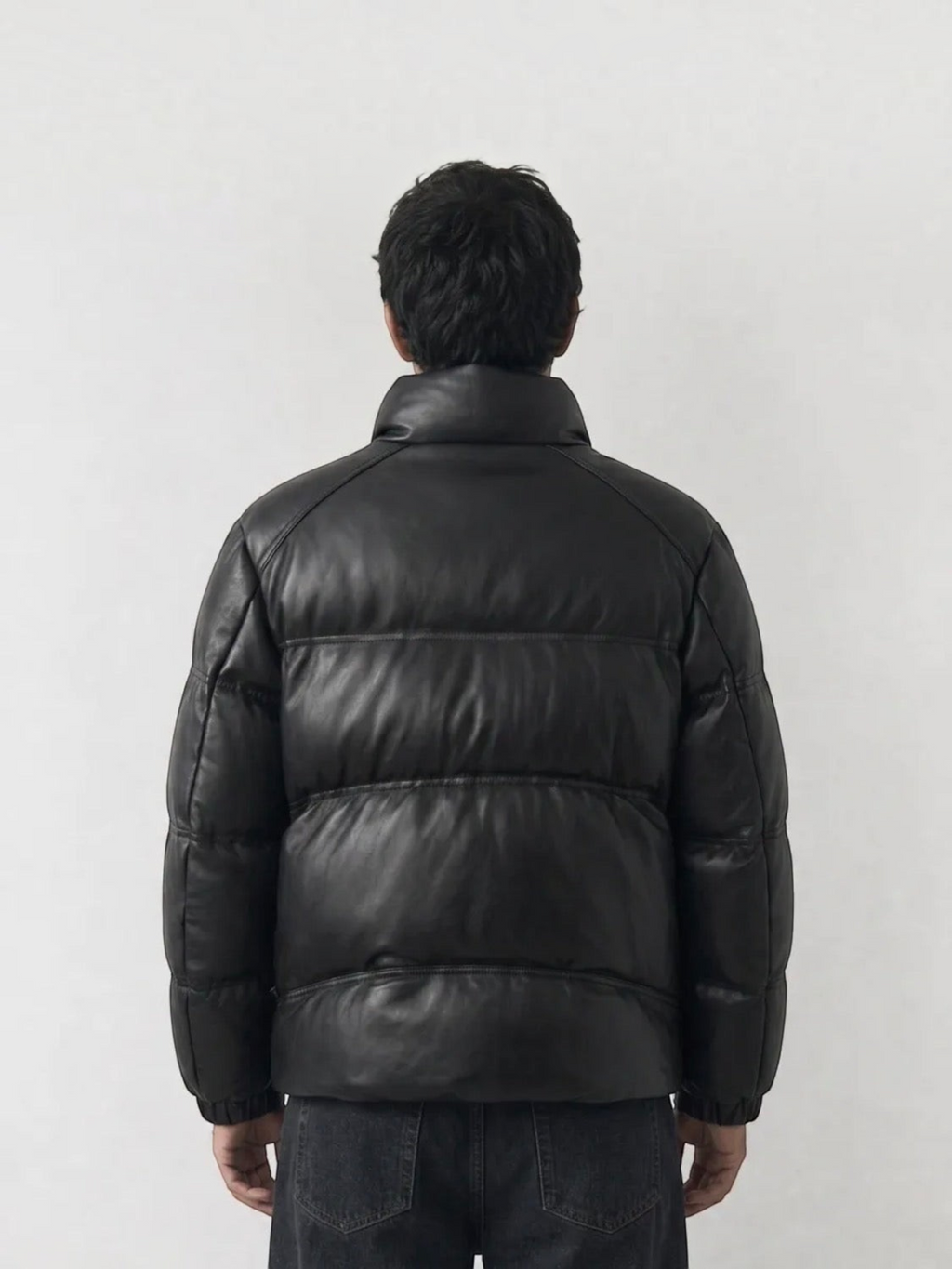 Back view of a man wearing a BROCK black faux leather puffer jacket with a high collar and quilted design.