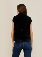Back view of a woman wearing a black BROCK faux fur zip-up gilet with a high collar and straight fit