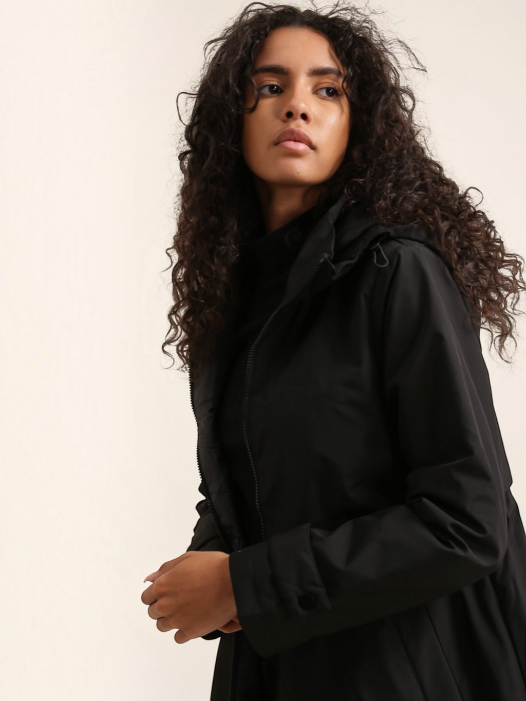 Model wearing a black BROCK long waterproof hooded jacket with a lightweight lining and adjustable hood.