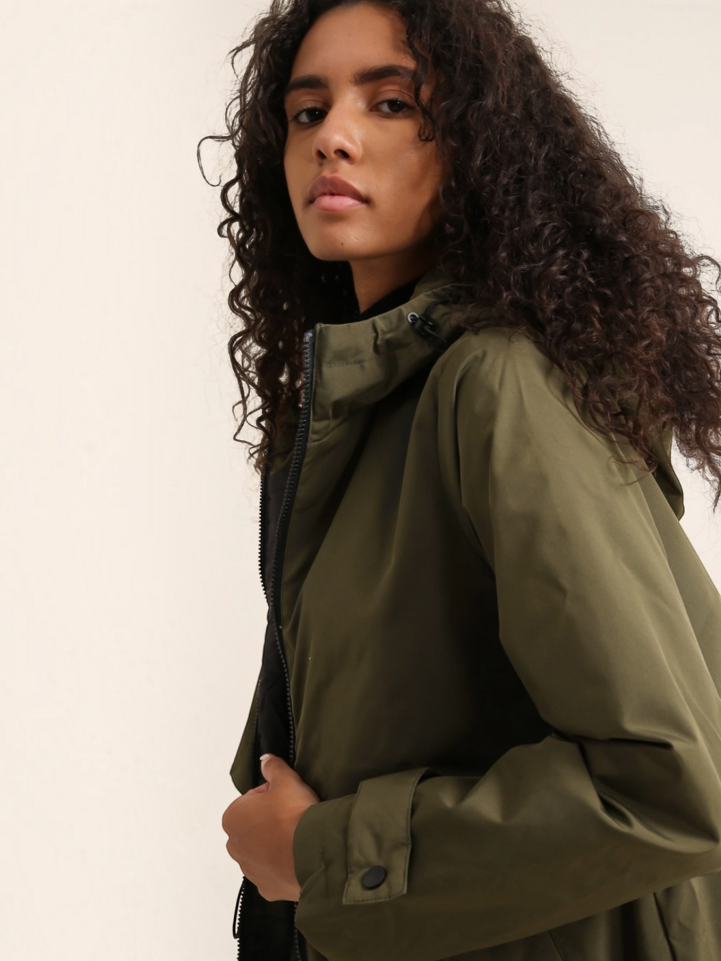 Model wearing a BROCK olive green long waterproof hooded jacket with a zip closure and adjustable hood