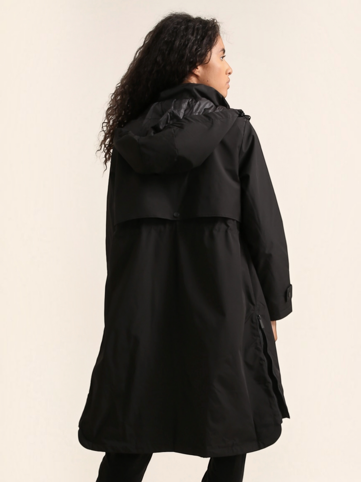 Model wearing a black BROCK long waterproof hooded jacket with a back vent and adjustable fit for rainy weather.