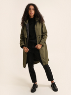 Model wearing a long olive green waterproof hooded jacket by BROCK, featuring a lightweight lining and loose fit.