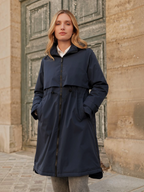 Model wearing a navy blue BROCK long waterproof hooded jacket with an adjustable drawstring waist and zip closure.