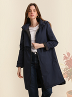 Model wearing a navy blue long waterproof hooded jacket by BROCK with a zip closure and adjustable waist.