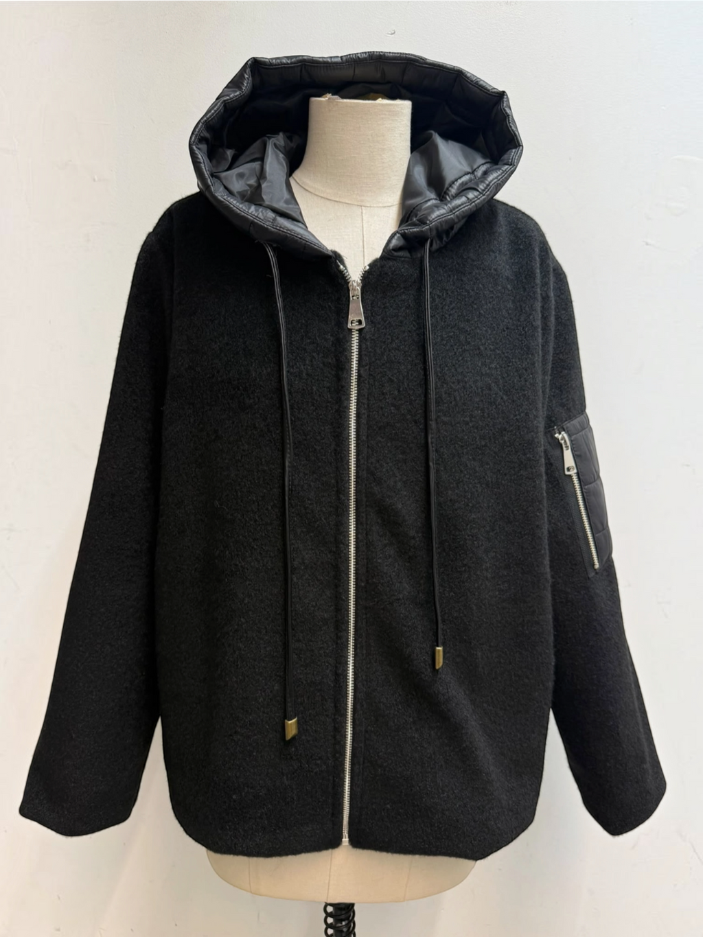 BROCK black felted wool blend zip-up jacket with a quilted hood, drawstring, and utility sleeve pocket on a mannequin