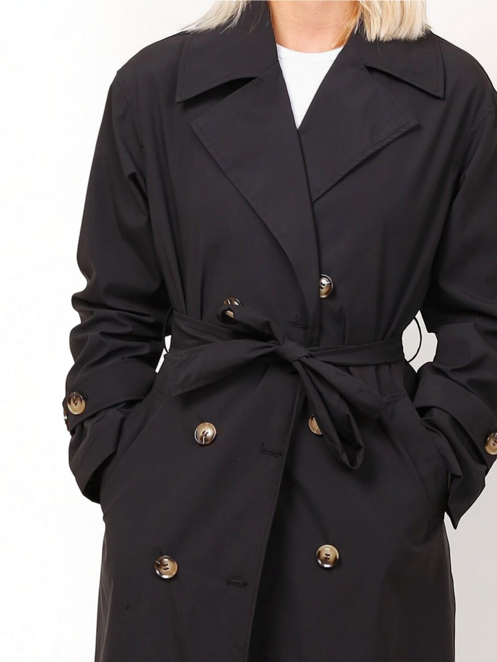 Trench long noir BROCK à double boutonnage avec ceinture à nouer et col tailleur porté par une femme
