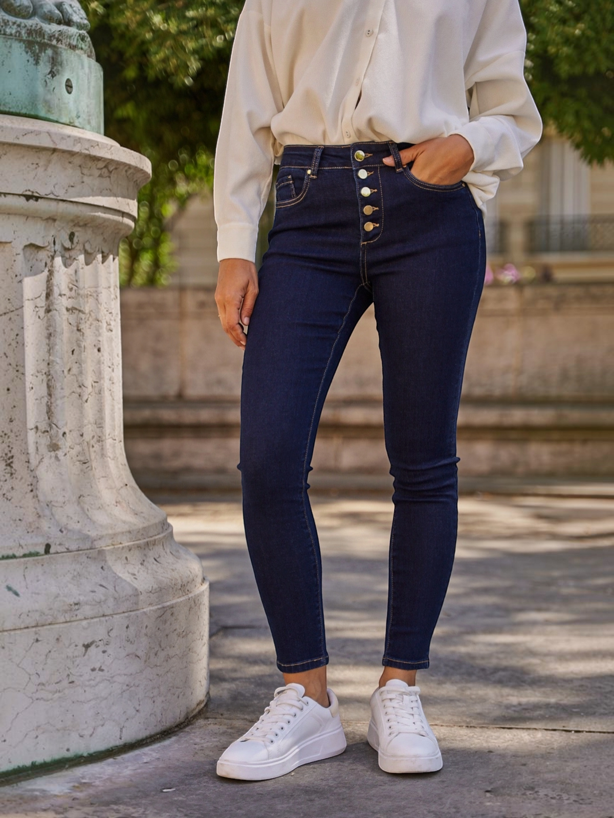 Jean slim taille haute BROCK R.DISPLAY en denim brut bleu foncé avec boutonnage apparent, porté avec des baskets