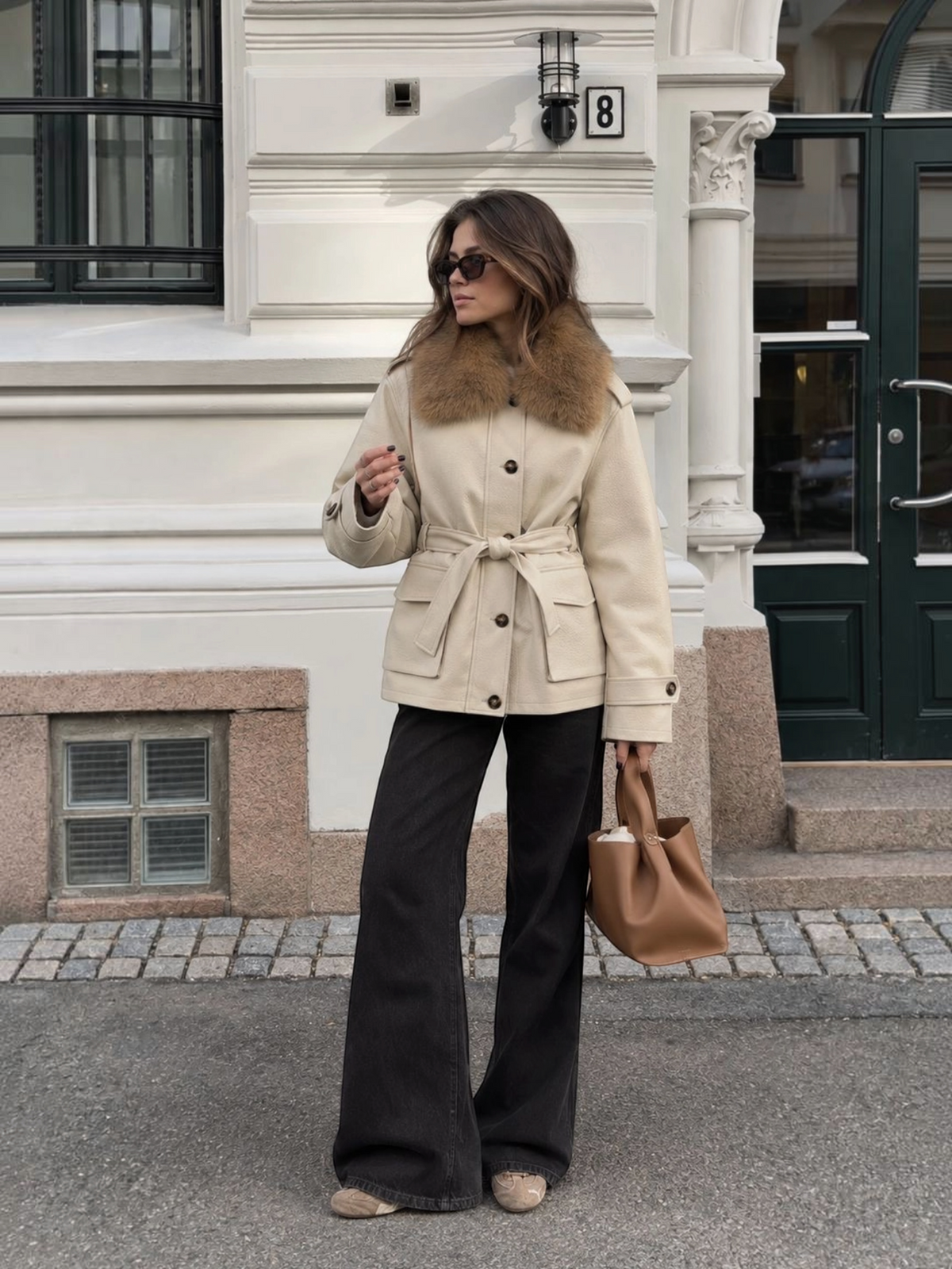 Femme portant un manteau mi-long BROCK en similicuir beige avec col en fausse fourrure et ceinture à nouer