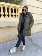 Femme portant une doudoune mi-longue matelassée kaki COPPEROSE de la marque BROCK avec un jean noir et des baskets