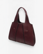 Sac cabas BROCK BESTINI bordeaux en cuir grainé avec surpiqûres blanches et fermoir décoratif, porté épaule
