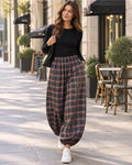 Femme portant un pantalon ample à carreaux BROCK avec taille élastiquée et bas resserrés, style décontracté en ville.