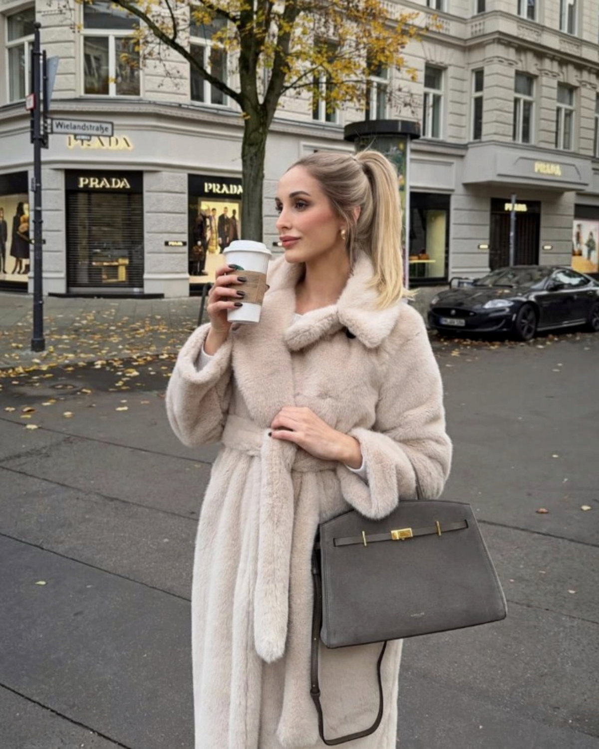 Femme portant un manteau long en fausse fourrure beige BROCK avec ceinture à nouer et grand col à revers en ville