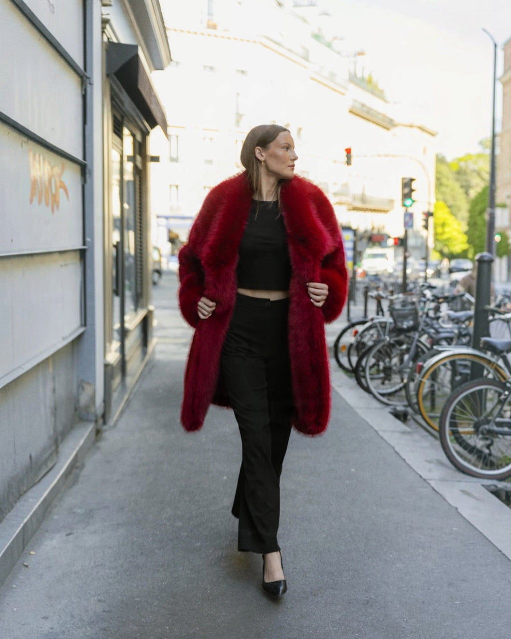 Femme portant un manteau mi-long BROCK en fausse fourrure rouge effet renard avec un grand col à revers en ville