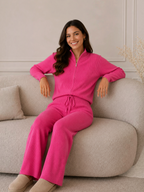 Ensemble BROCK en maille côtelée rose vif avec gilet zippé et pantalon droit porté par une femme sur un canapé