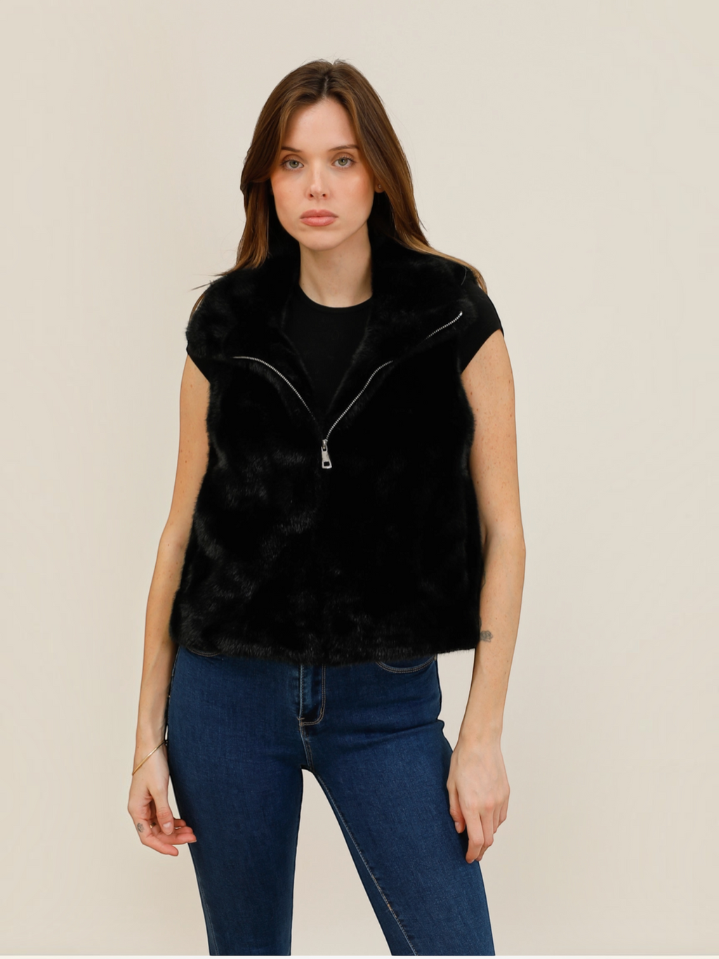 Model wearing a black BROCK faux fur zip-up gilet with a high collar over a black t-shirt and blue jeans