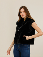 Model wearing a black BROCK faux fur zip-up vest with a high collar and side pockets over a black t-shirt and jeans.