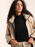 Model wearing a beige BROCK ATTRAIT PARIS long waterproof hooded jacket with a black lining over a black top