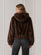 Veste courte zippée en fausse fourrure marron à capuche de la marque BROCK portée par une femme de dos