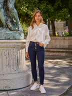 Femme portant un jean slim taille haute BROCK en denim brut avec boutonnage apparent, associé à une chemise blanche