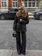 Femme portant un manteau mi-long en similicuir noir BROCK avec col en fausse fourrure et ceinture nouée en ville