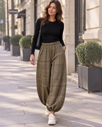 Femme portant un pantalon BROCK ample à carreaux avec taille élastiquée et bas resserrés dans une rue urbaine.