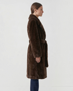 Manteau long BROCK en fausse fourrure marron avec ceinture à nouer et col à revers porté de profil