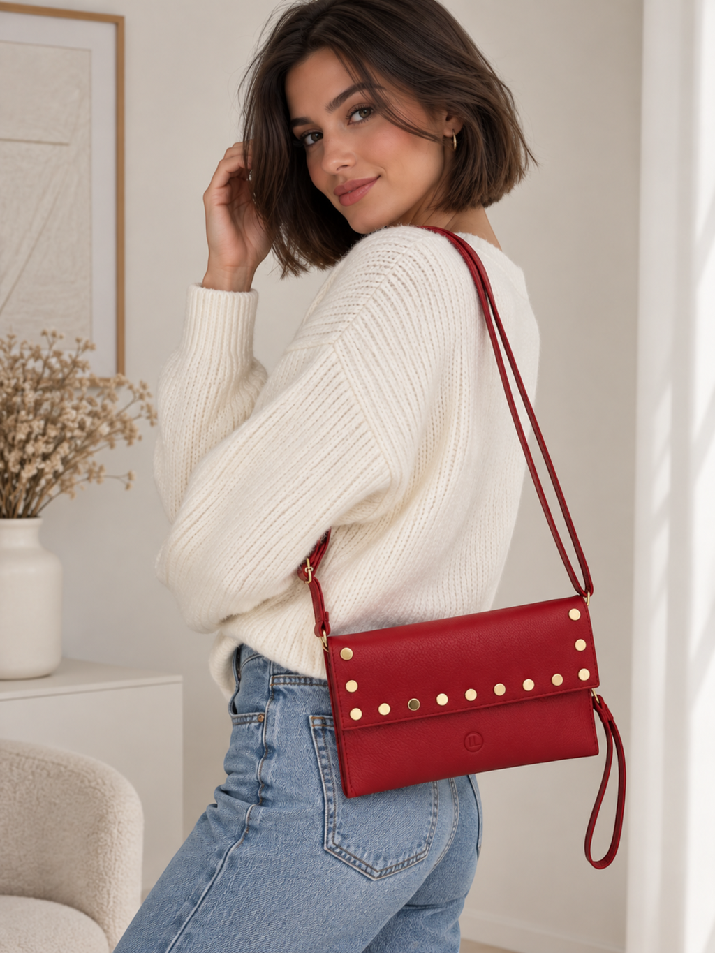 BROCK LOUISA LEE red grained leather clutch with gold studs worn as a shoulder bag by a woman in a white sweater