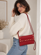 BROCK LOUISA LEE red grained leather clutch with gold studs worn as a shoulder bag by a woman in a white sweater