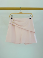 Short taille haute rose BROCK avec boutons dorés décoratifs, en polyester, suspendu sur un cintre.