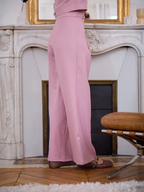 Pantalon fluide rose de l'ensemble BROCK avec détails de boutons dorés, vue de profil dans un intérieur élégant