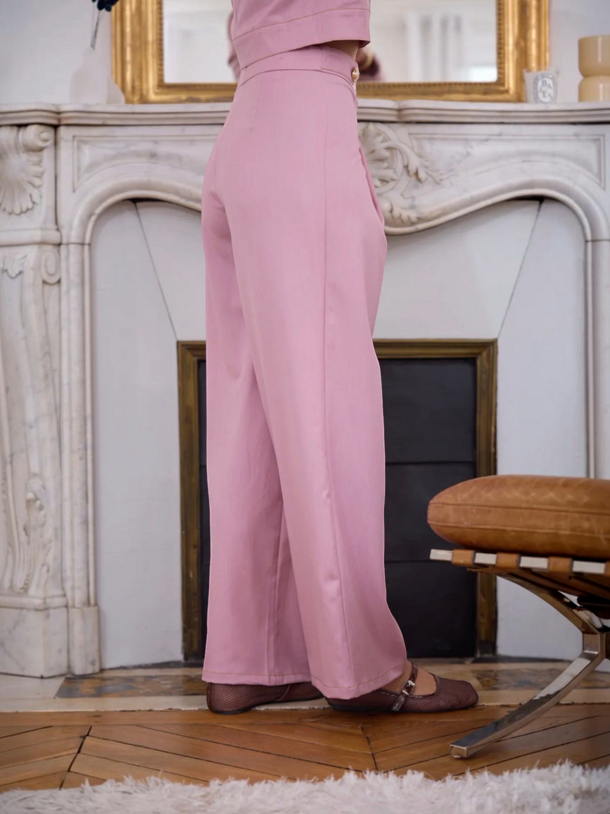 Pantalon fluide rose de l'ensemble BROCK avec détails de boutons dorés, vue de profil dans un intérieur élégant
