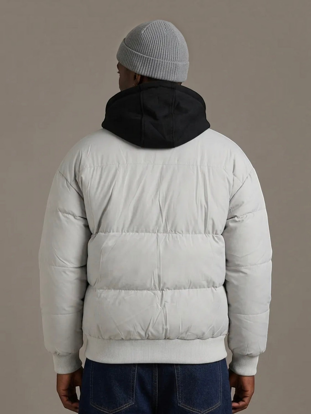 Back view of a man wearing a grey BROCK puffer jacket with a detachable black hood and ribbed hem