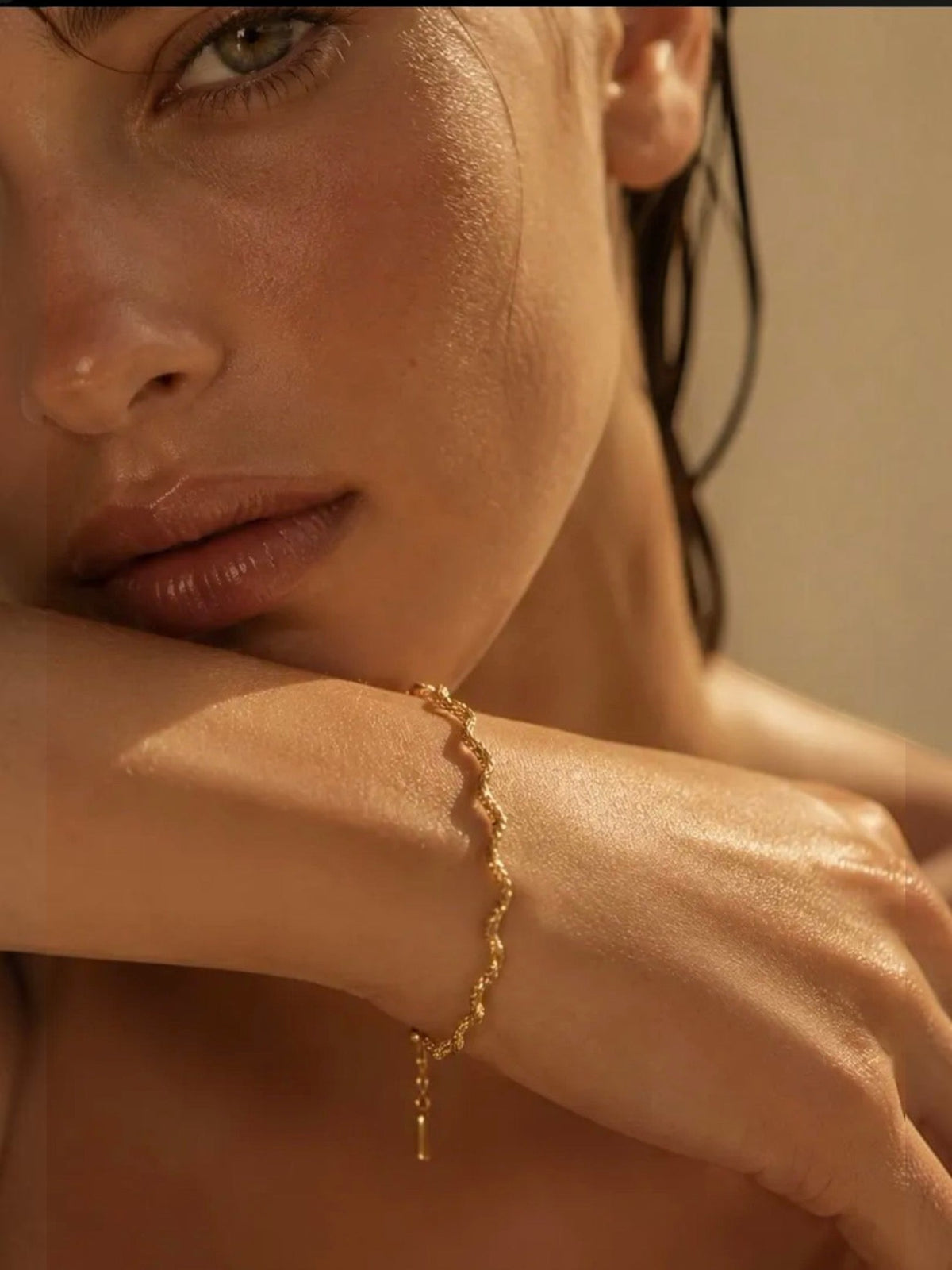 Bracelet fin doré en acier inoxydable porté au poignet par une femme, design torsadé élégant et résistant
