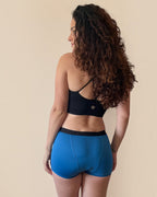 BROCK ANAISSA blue menstrual shorts for teens worn by a woman with long curly hair, back view.