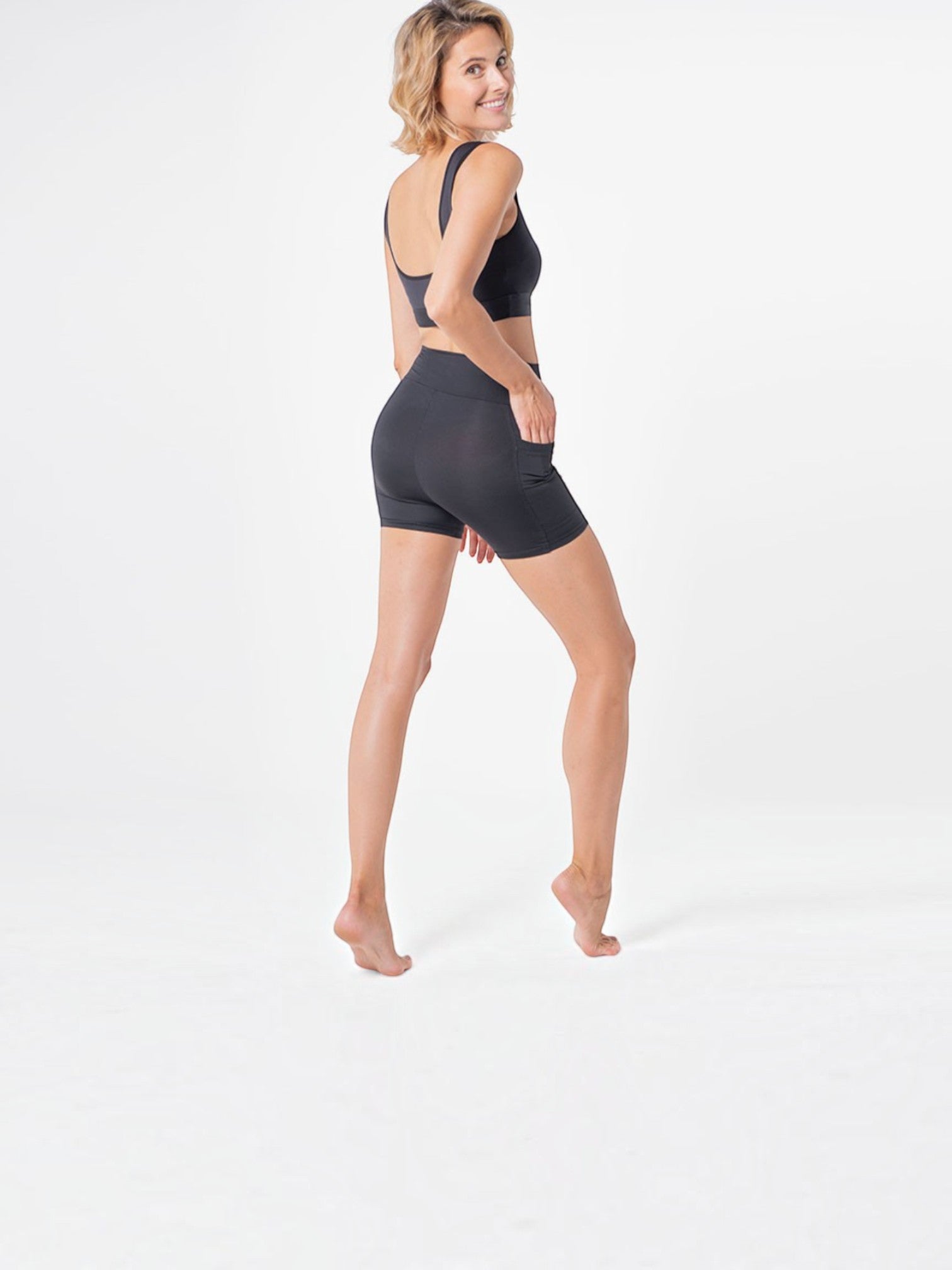 Woman wearing black BROCK ANAISSA Halasana sports shorts with side pocket, made from firming 3D Ymax fabric.