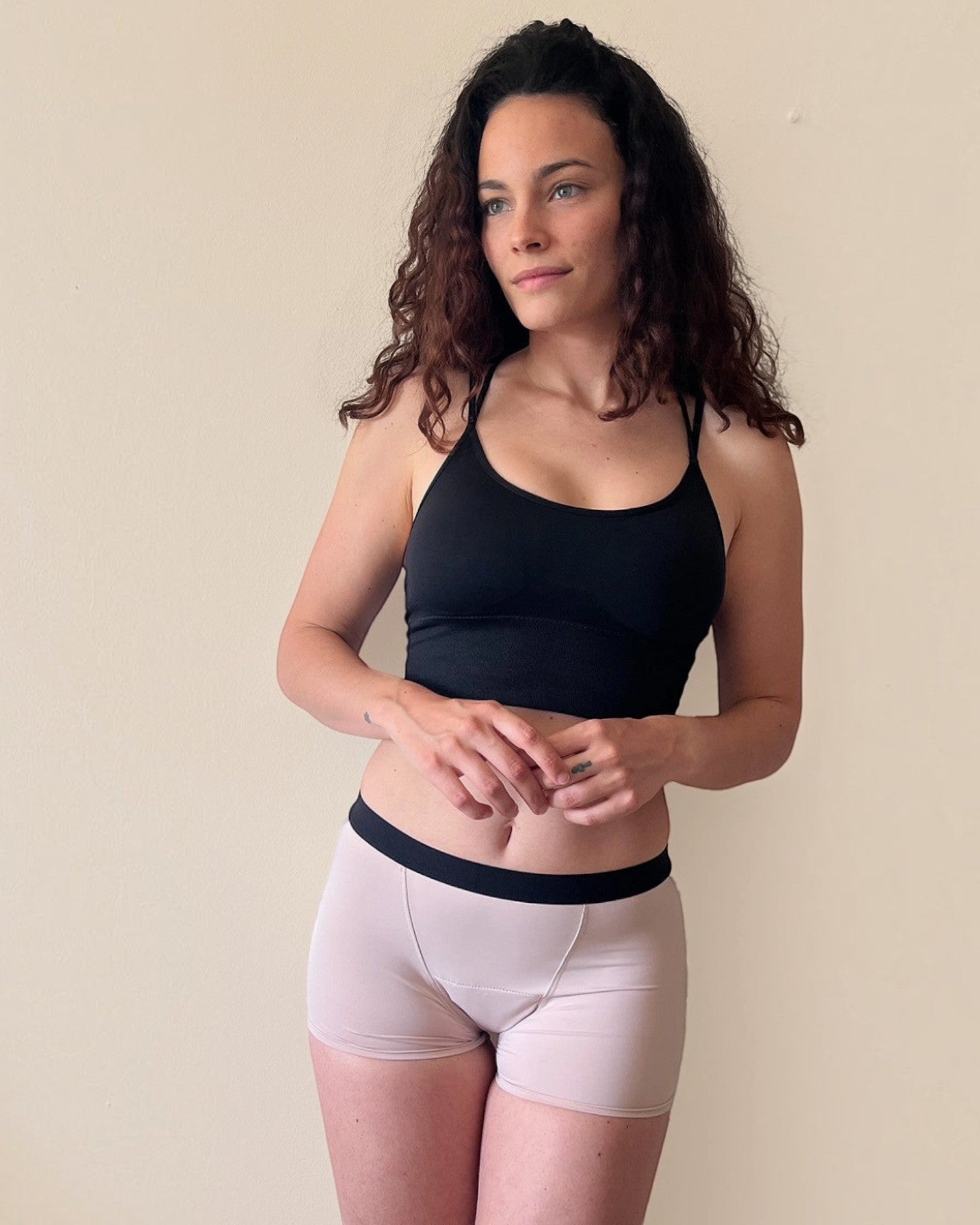 BROCK ANAISSA teen menstrual shorts in light pink with black waistband worn by a woman with curly hair