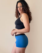 BROCK ANAISSA teen menstrual shorts in blue, worn by a woman with curly hair, showing a slim, comfortable fit.